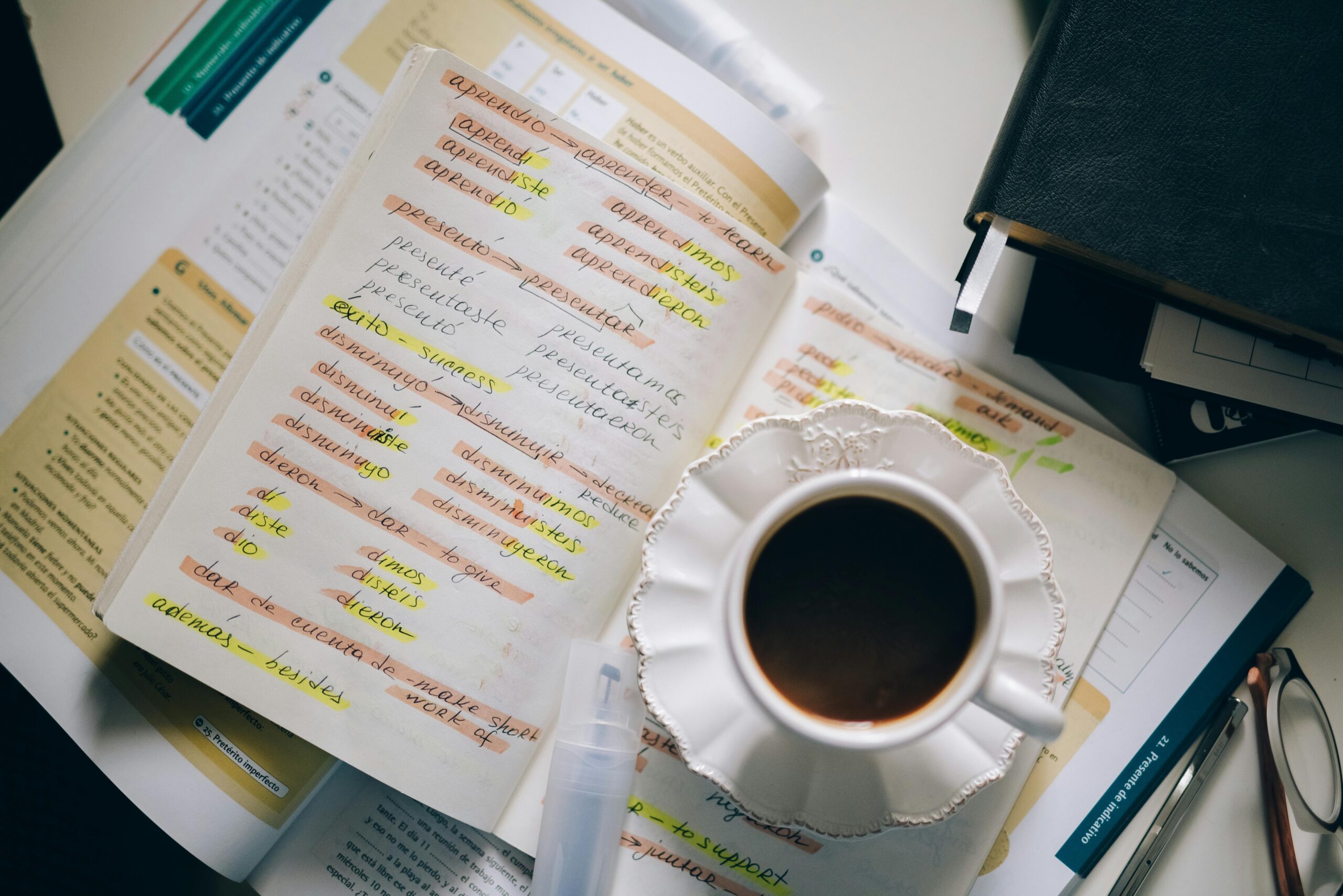 Flat-lay of a Spanish notebook, phone with voice notes, and a coffee