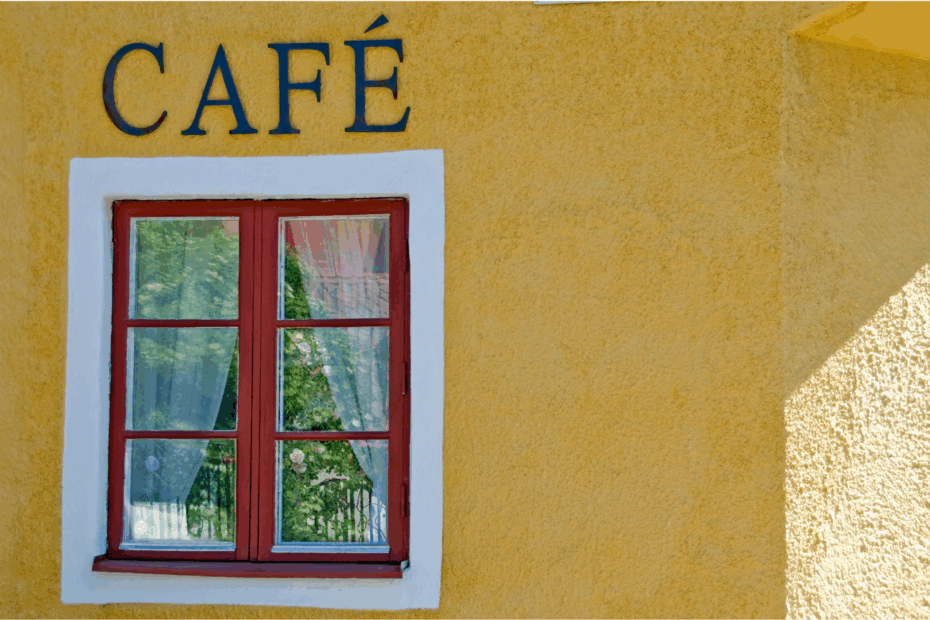 Smiling waiter serving coffee at a Spanish café as a customer says gracias