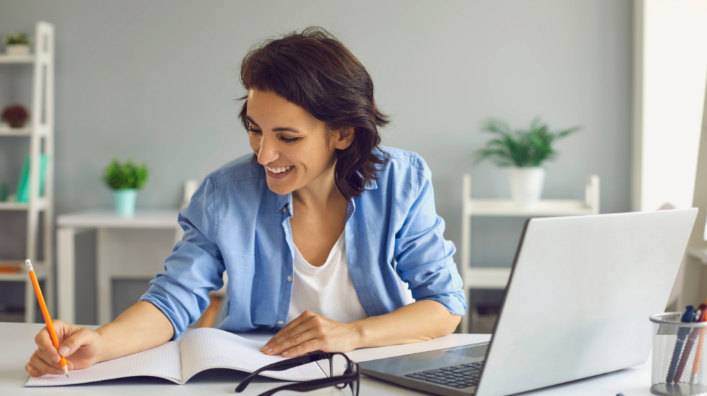 a learner writing in a notebook during an online spanish lesson.